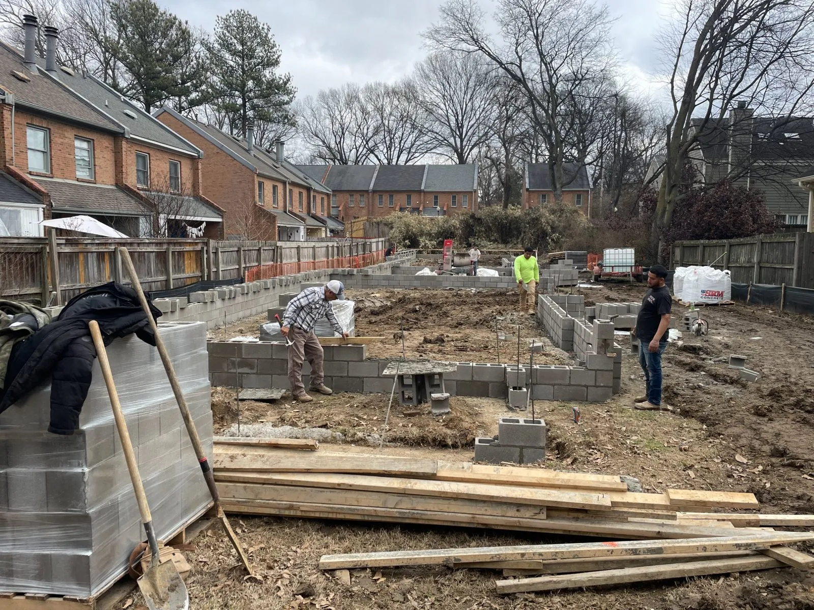 Concrete masonry foundation walls going up on a Memphis residential lot, with crew laying block and materials staged on site